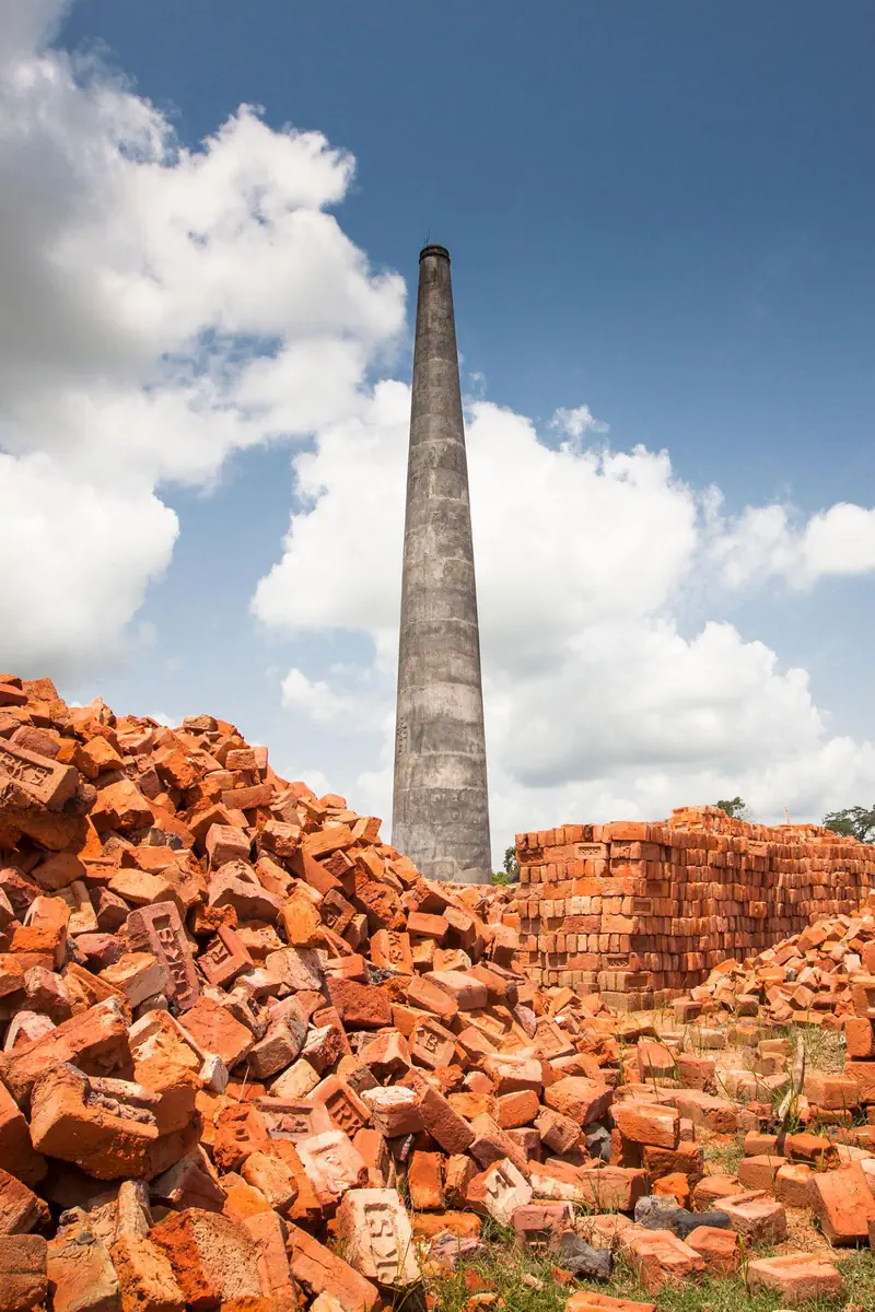 Brick kiln chimney rising above stacks of fired bricks