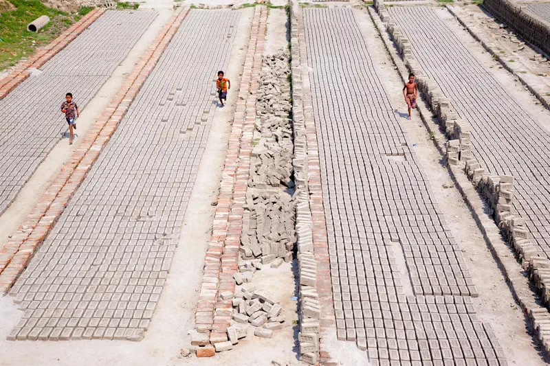 Children walking among drying bricks